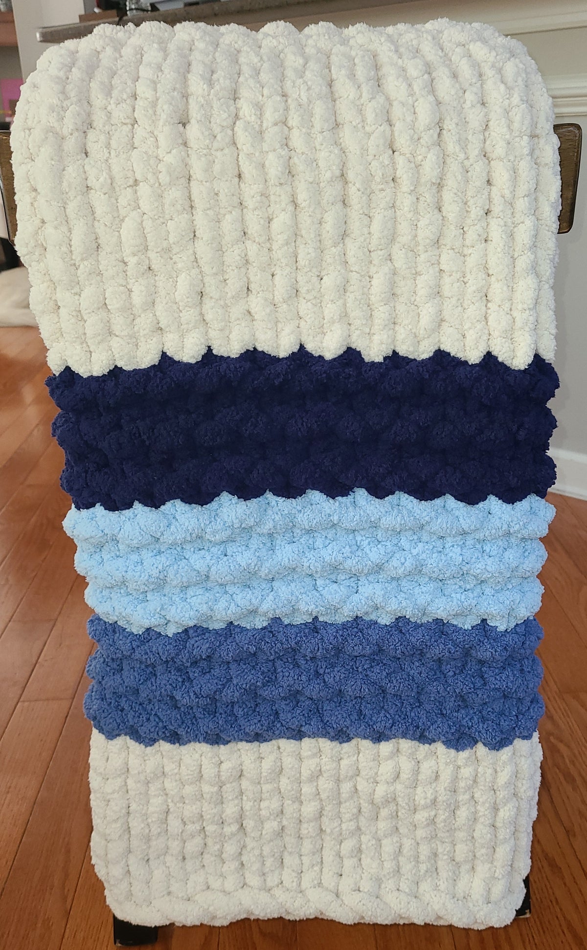 Quiet Tide blanket — deep navy and sky blue on cream — hung full length showing the ridge bands