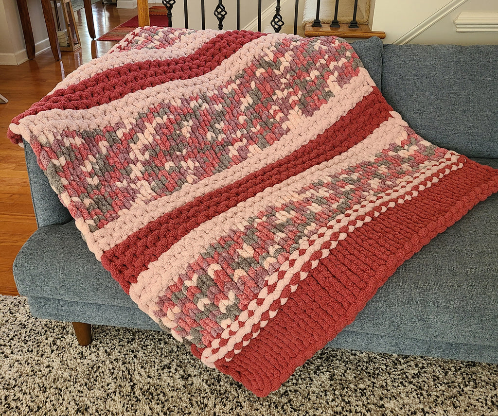 Equinox Blossom — mulberry, dusty pink, and sage — draped over a gray sofa showing the full pattern