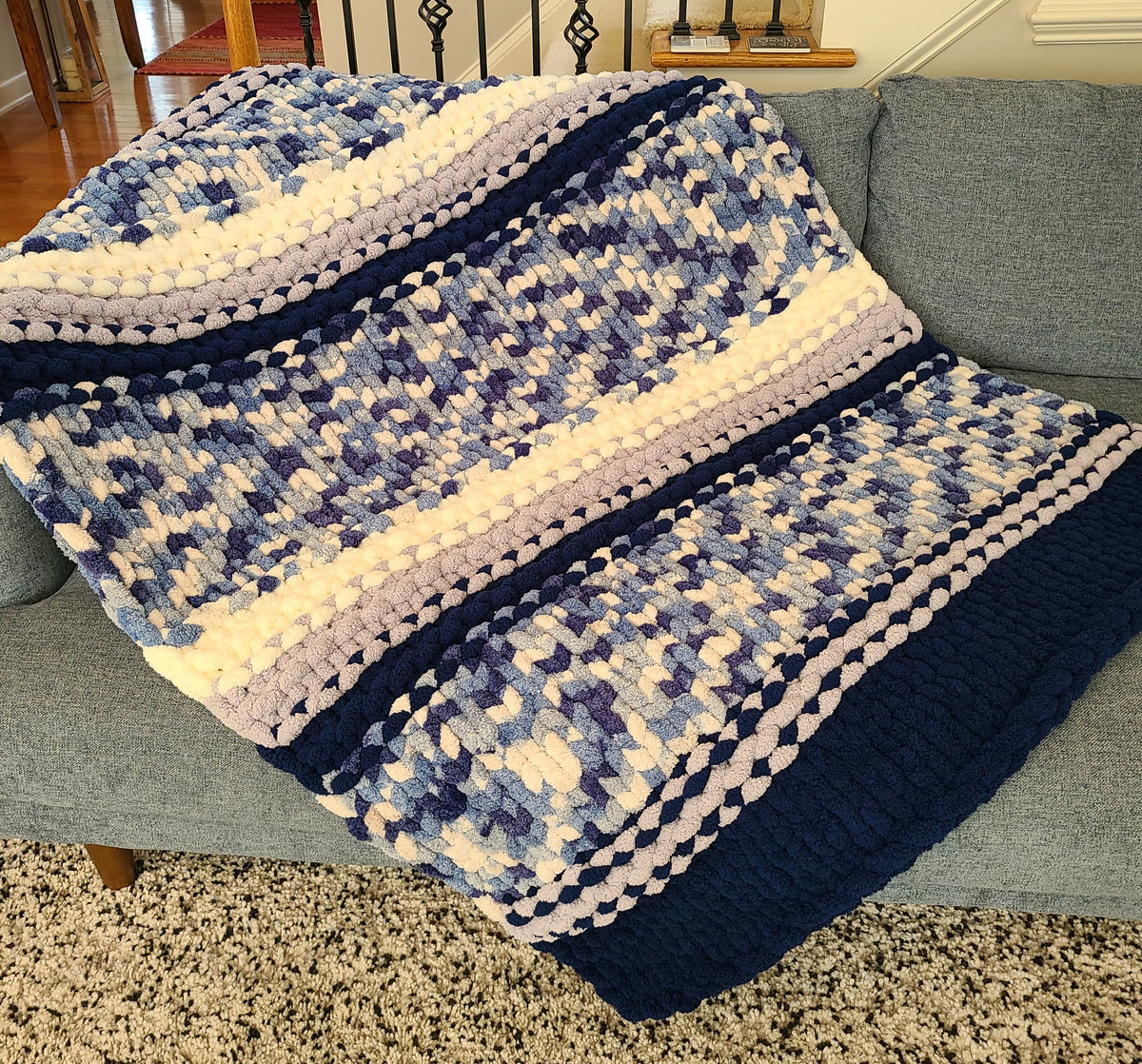 Winter Solstice — deep navy, light gray, and cream — draped over a gray sofa showing the full pattern