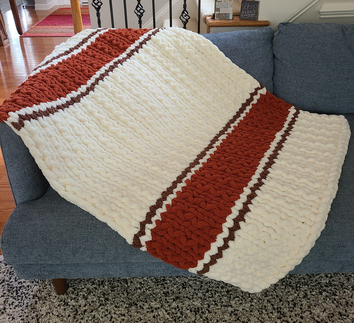 Autumn Ember — copper, coffee brown, and vintage white — draped over a blue sofa