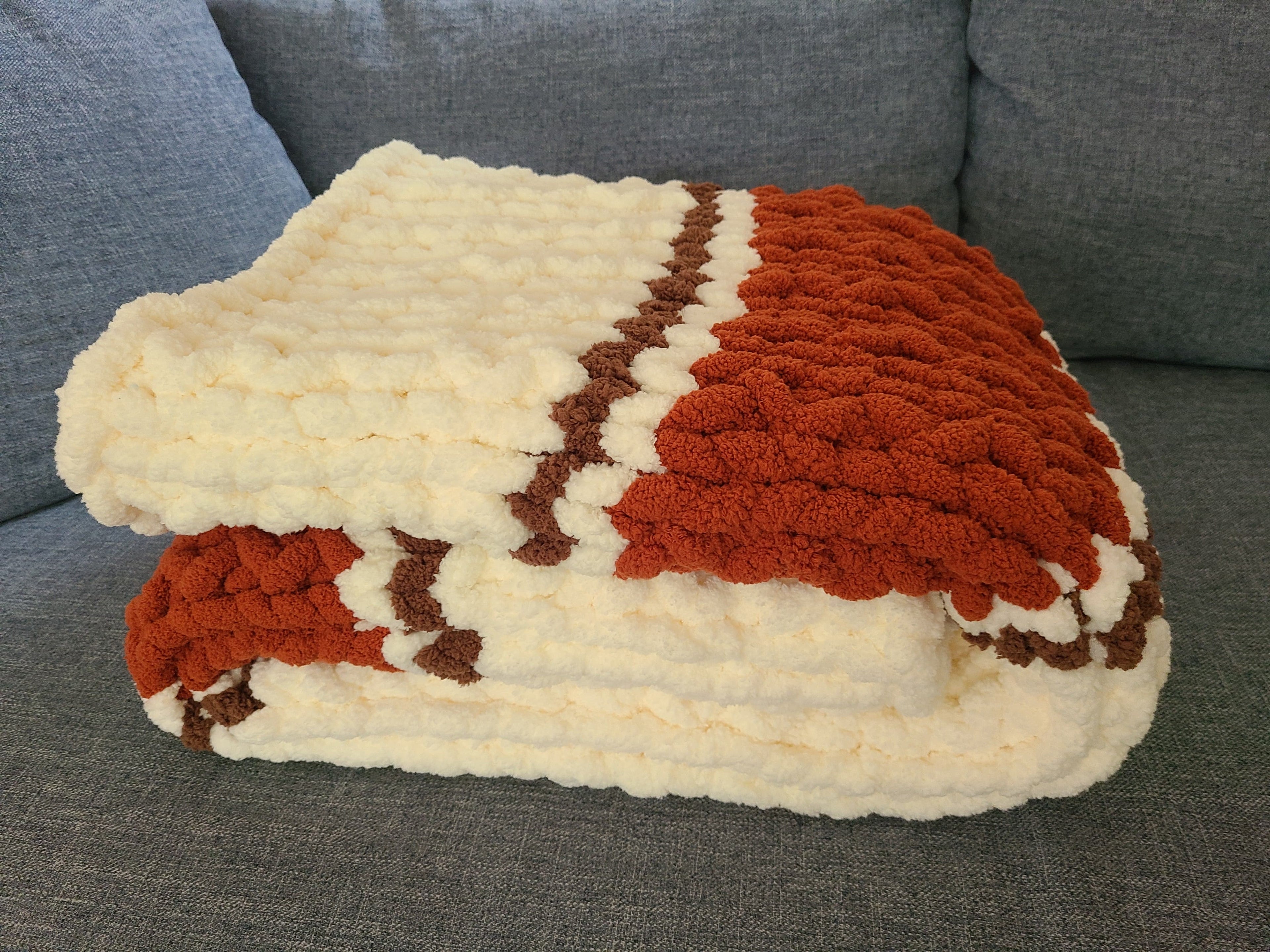 Autumn Ember — copper, coffee brown, and vintage white — folded neatly on a sofa showing the knit depth