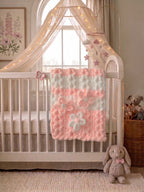 Blushing Mist baby blanket — white and soft pink — draped over a white crib rail in a soft nursery