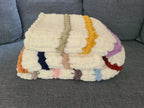 Timeless Eras — multicolour raised stripes on cream — folded on a gray sofa showing the raised ridge texture