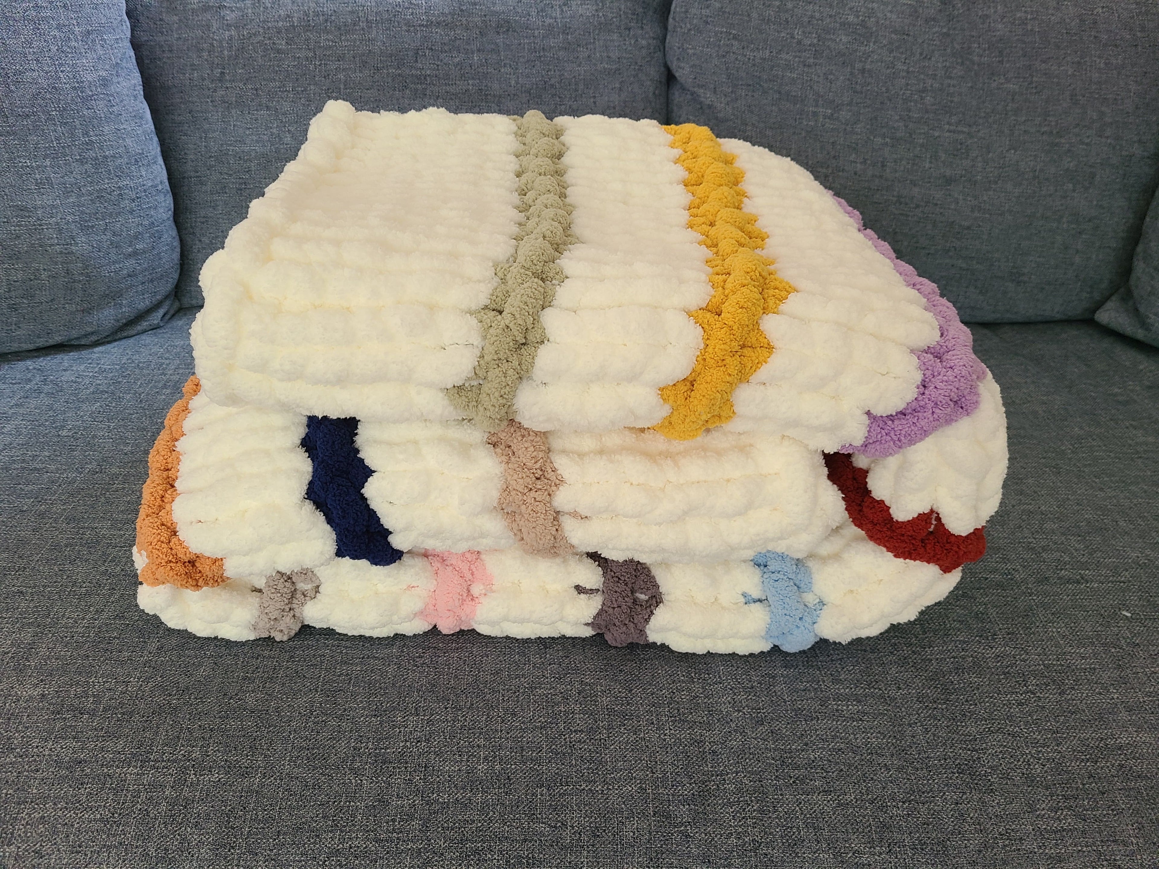 Timeless Eras — multicolour raised stripes on cream — folded on a gray sofa showing the raised ridge texture